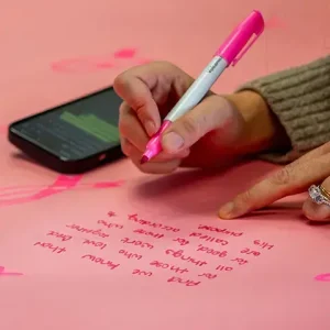 Woman writing message on pink paper