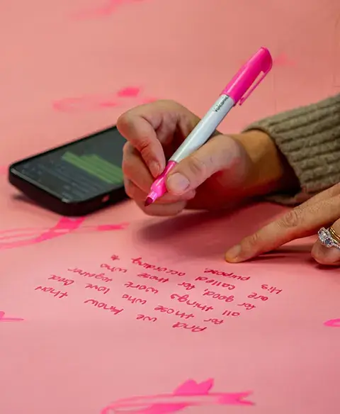 Woman writing message on pink paper