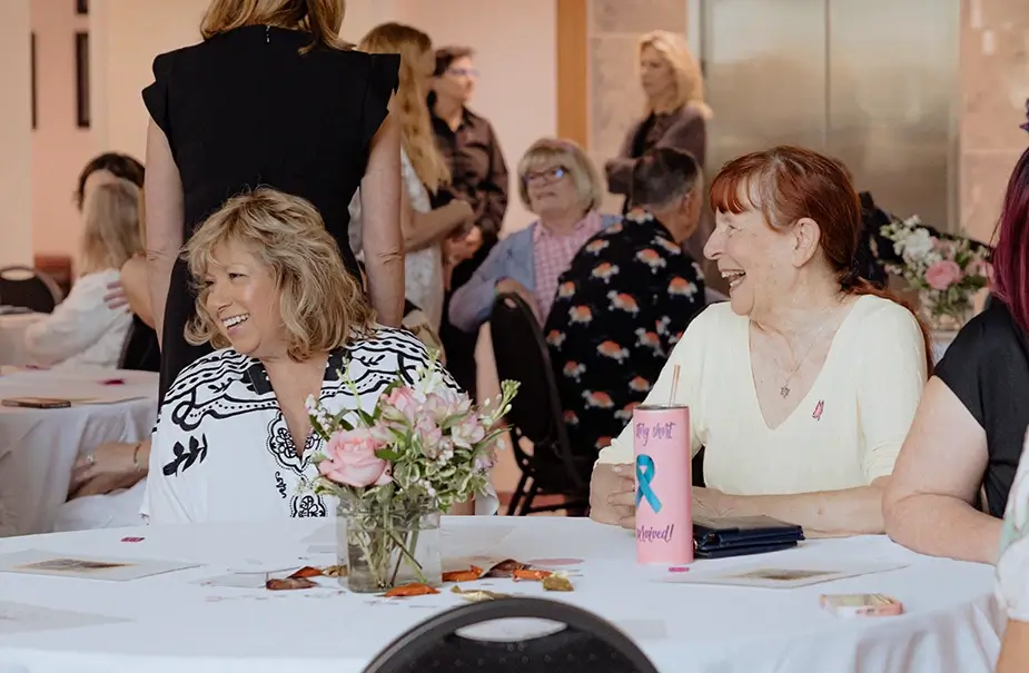Two women laugh while sitting at their table at a Survivors Brunch