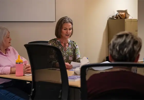 Woman reading from book at support group<br />

