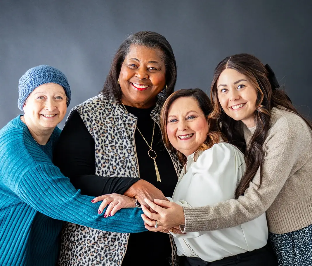 Four breast cancer survivors hug in a group photo