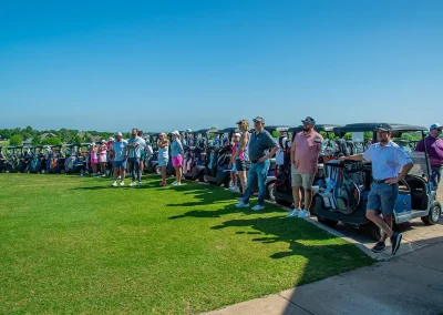 A line of golfers and golf carts on a course