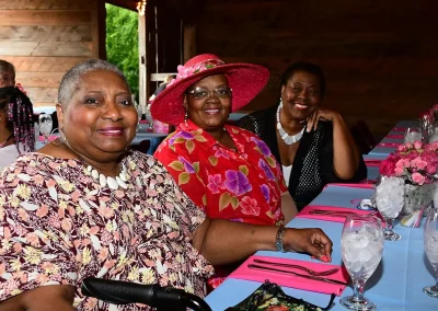 Three women smile at an outdoor brunch
