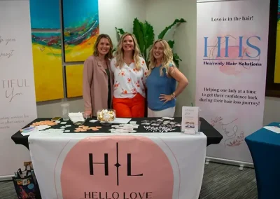 Three vendors smile while standing behind the Hello Love booth