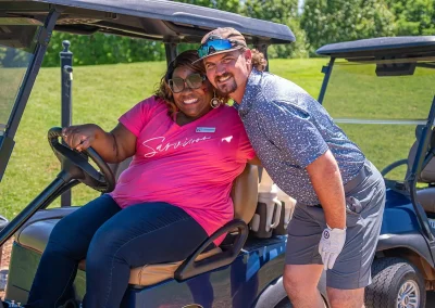 A man hugs a woman sitting in a golf cart