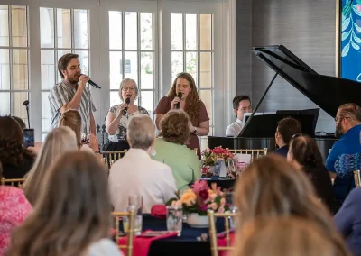 Three people singing along with a piano