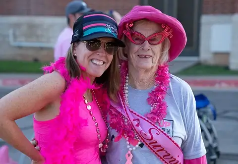 Two women are dressed in fun pink clothes to support runners