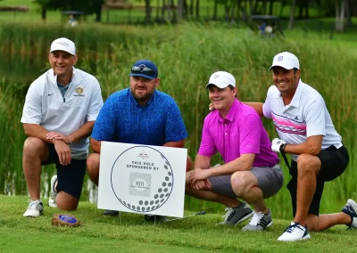 Four men kneel by their sponsor sign