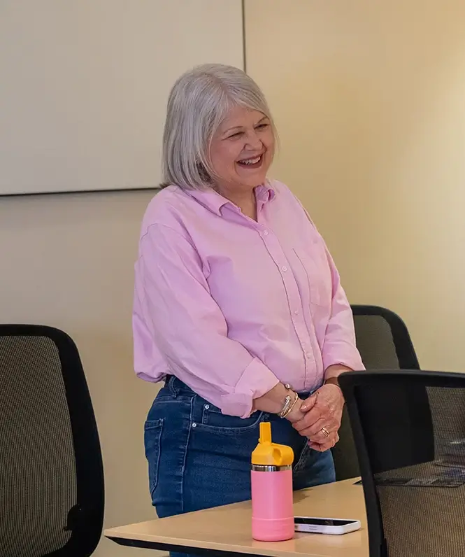 A support group leader stands and smiles