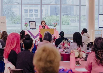 A woman gives a speech at the Expo as dozens of attendees listen