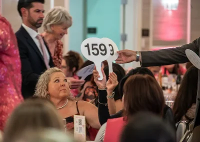 A woman raises a bidding number