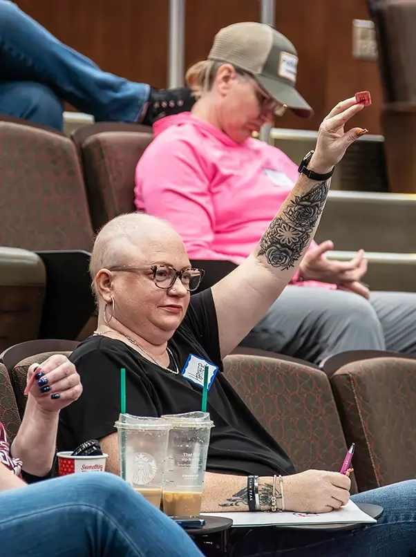 A breast cancer survivor holding up her hand with a raffle ticket