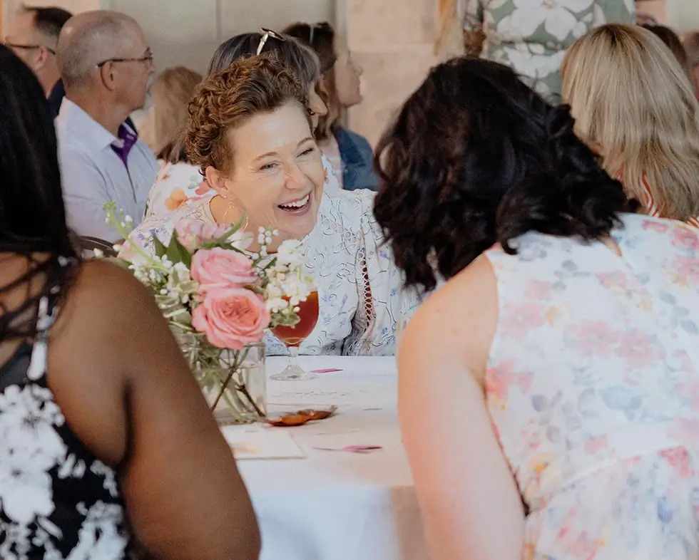 Two women laugh while chatting at a luncheon