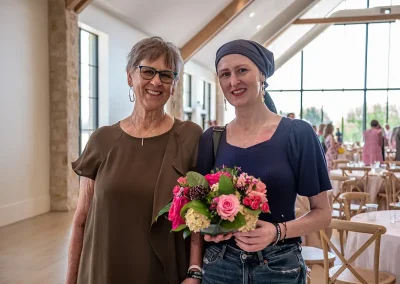 Two survivors smile while one holds a flower bouquet