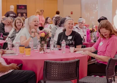 Three women laugh while sitting together at a table