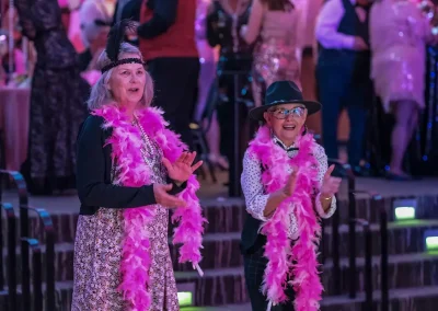 Two survivors wearing pink boas on the dance floor
