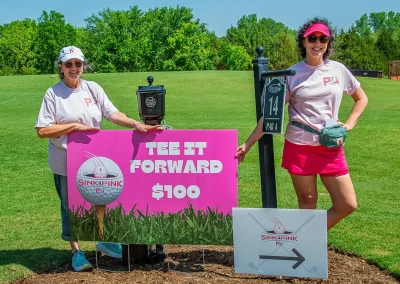 Two women smile while standing by entrance sign