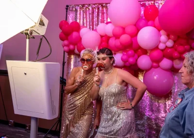 Two women in costume smile while using props at a photobooth
